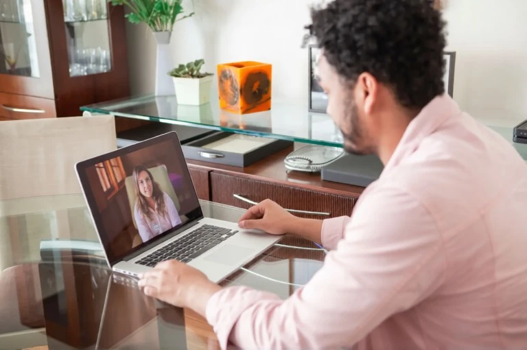 Man attending an online therapy session with a therapist on a laptop.