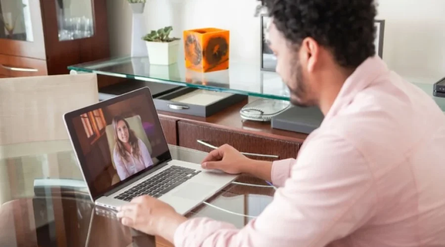 Man attending an online therapy session with a therapist on a laptop.
